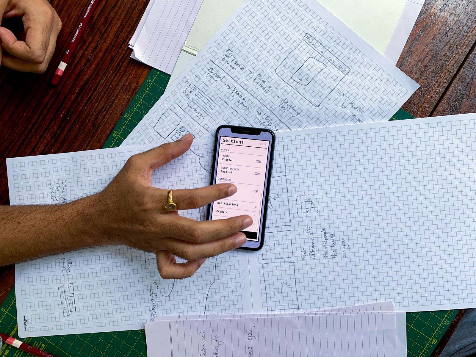 Smartphone held over mobile app design sketches during a website and app build